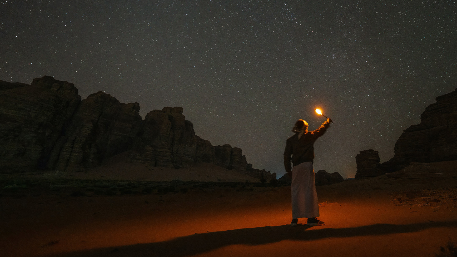 رجل يحمل عصا مضيئة في صحراء نيوم في الليل
